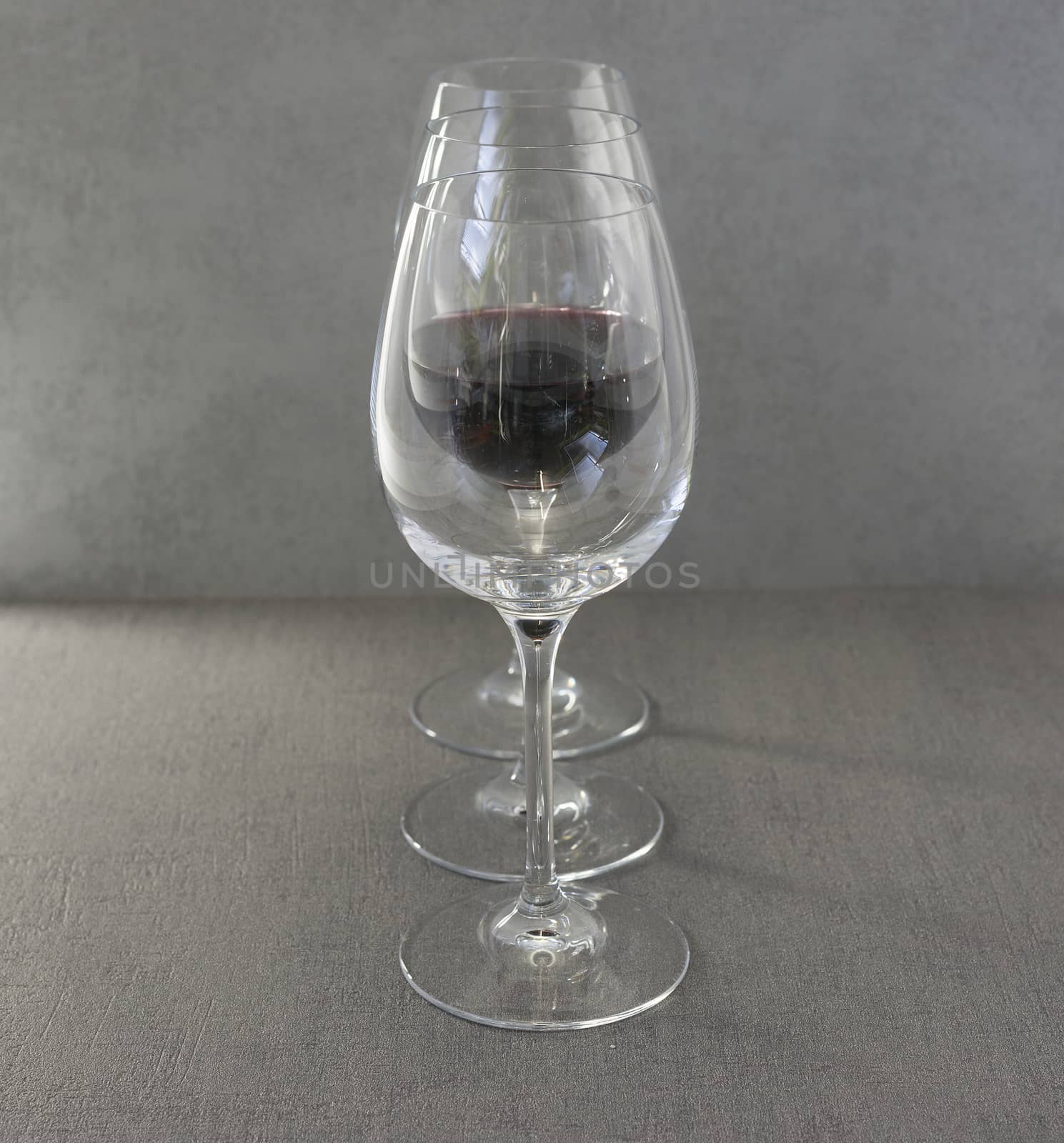 three glasses with one filled with red wine