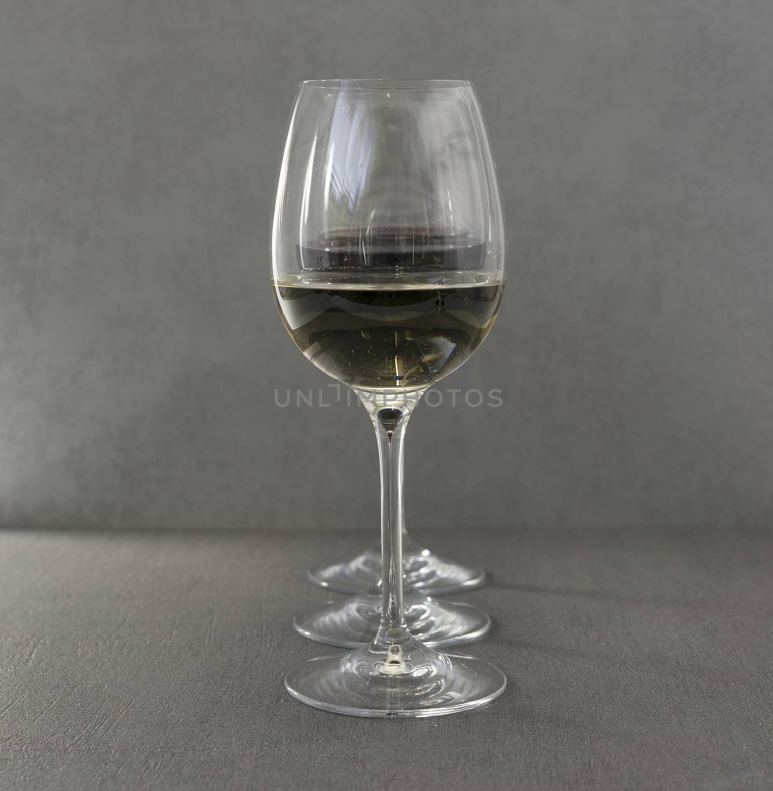three glasses one with white and two with nred wine in arow