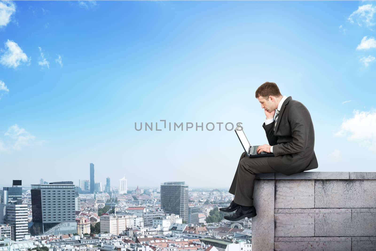 Businessman working on laptop and sitting on roof