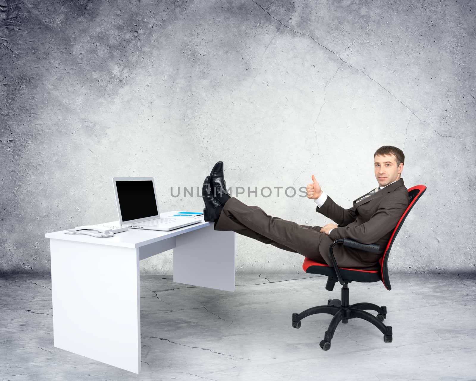 Businessman sitting on chair with table and laptop with legs upon grey background