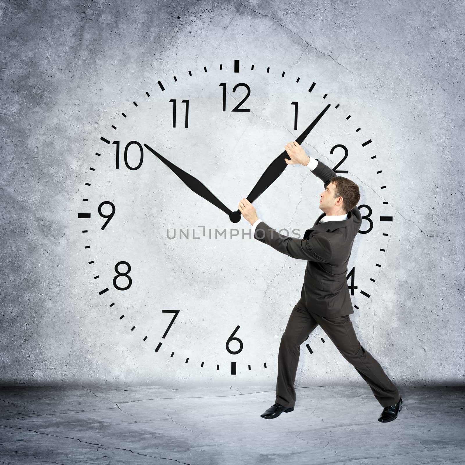 Businessman holding clock hand on grey wall backgound