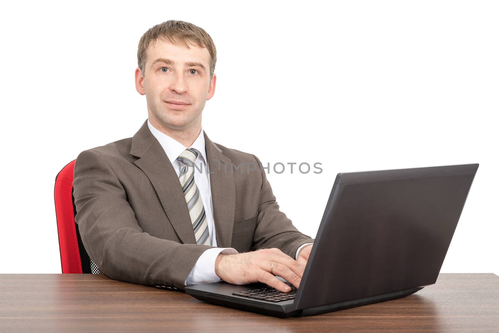 Businessman working on laptop and looking at camera isolated on white background