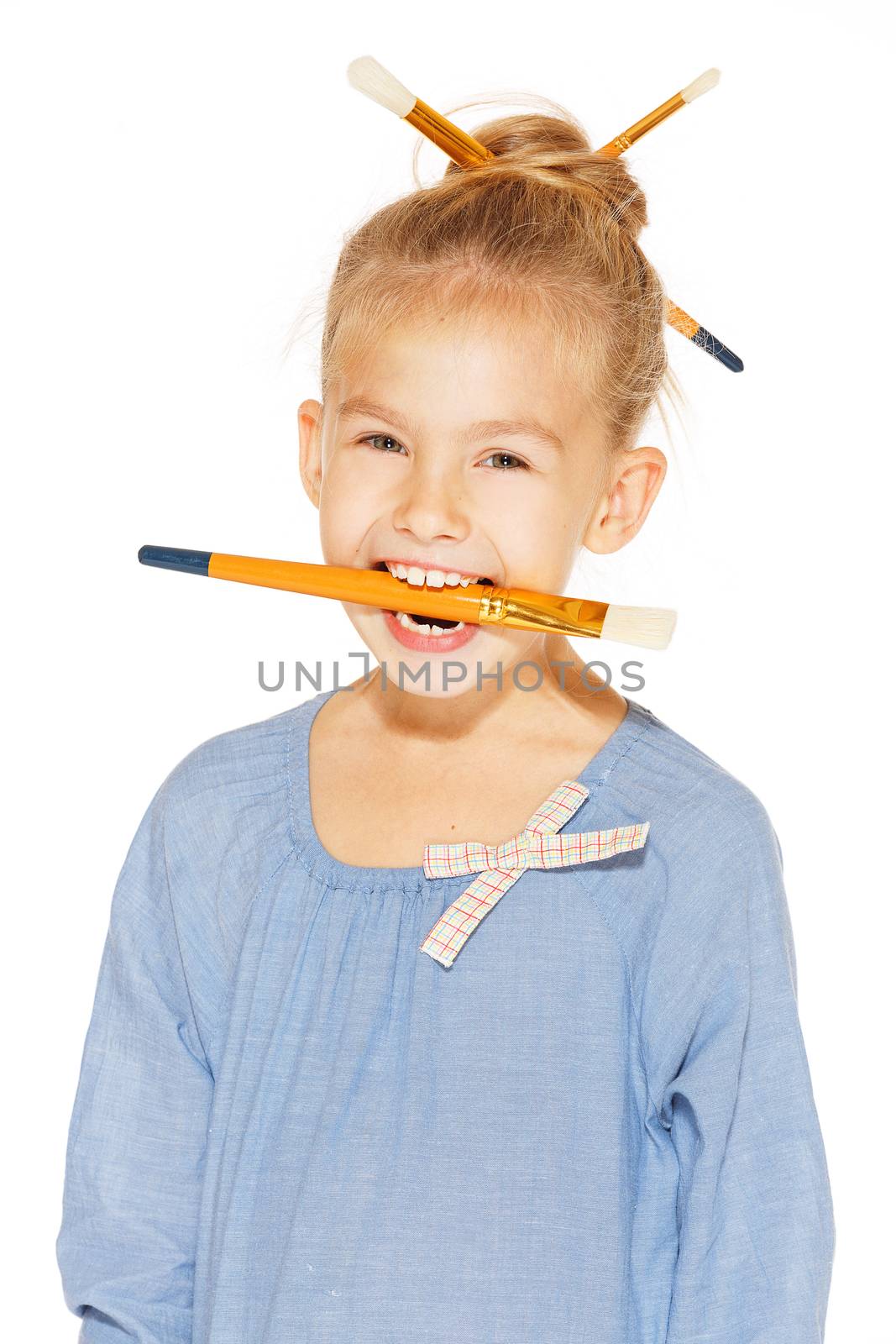 Little girl painter in a blue dress with paints and brushes