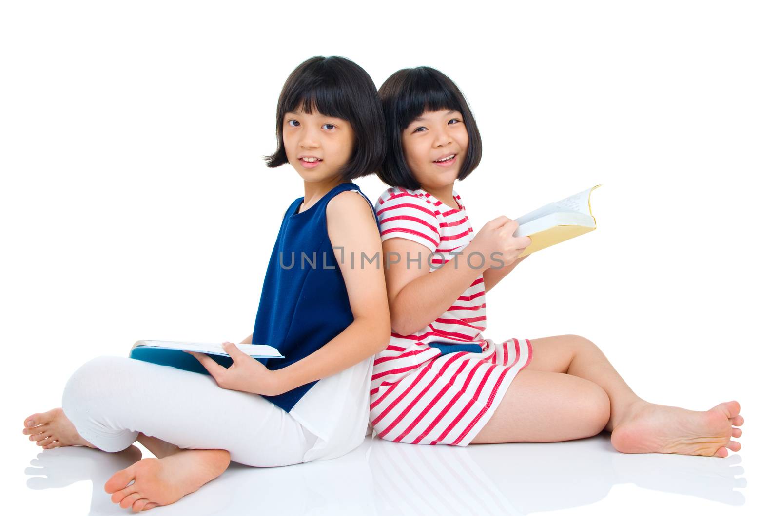 Asian girls sitting on the floor and reading. Isolated on white background.