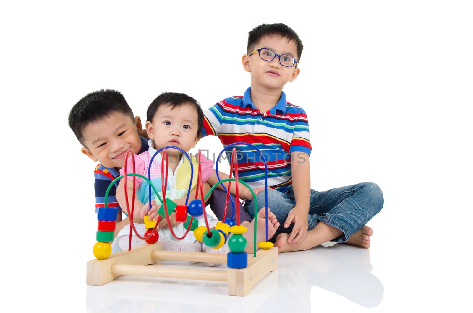 Asian kids sitting on the floor, playing with toy.