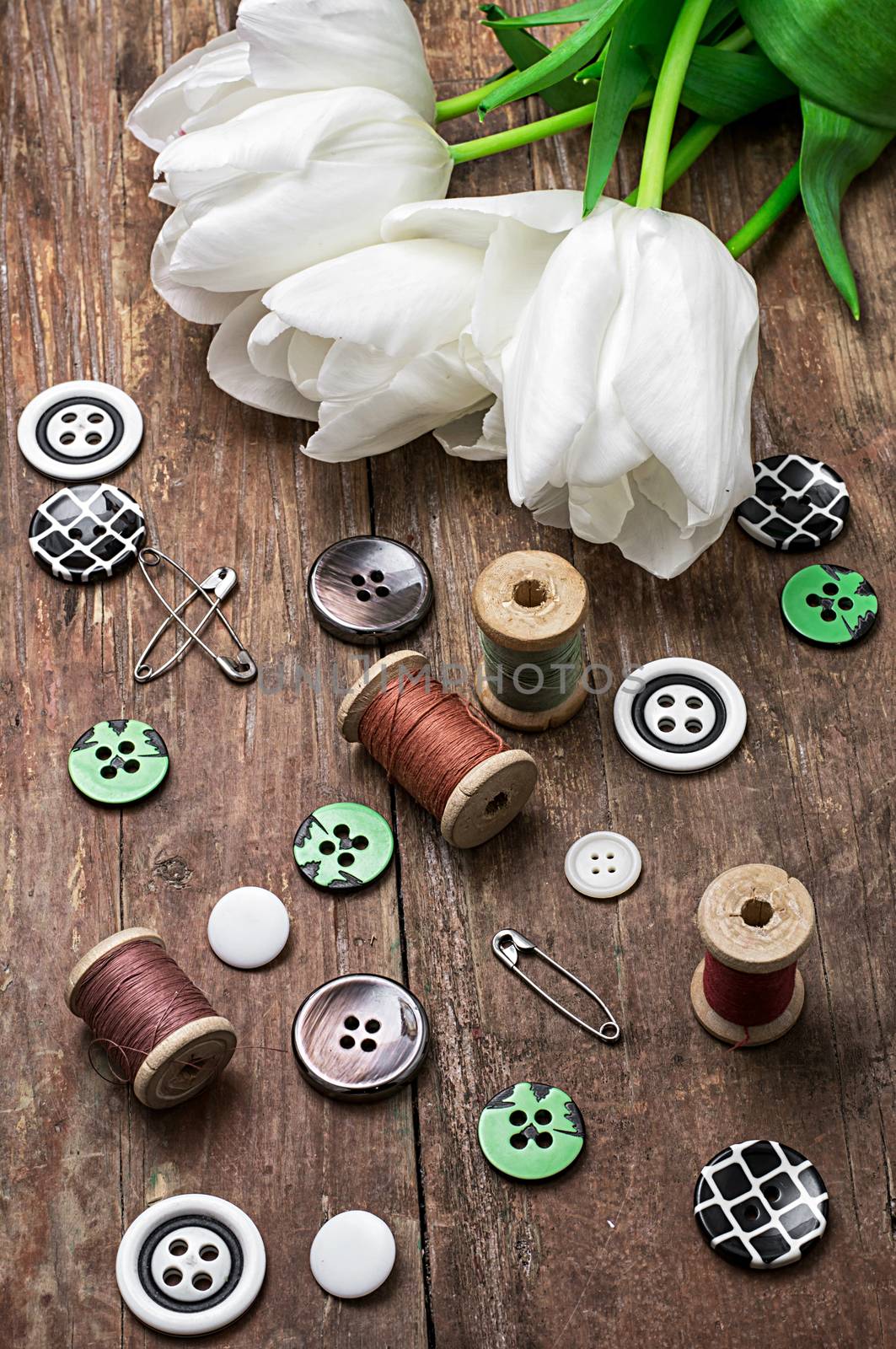 sewing accessories with a bouquet of fresh flowers.the image is tinted in vintage style