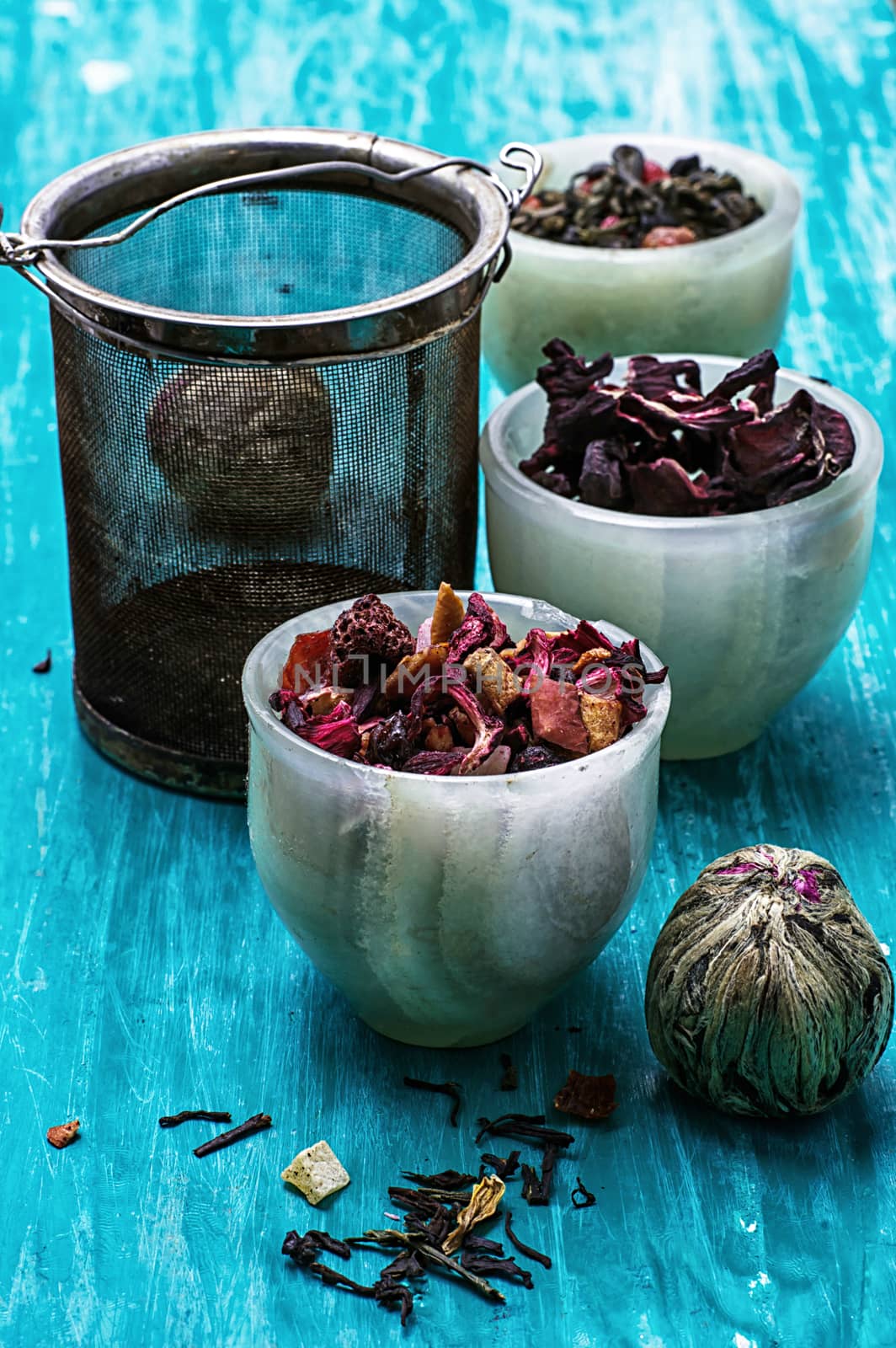 variety of dry tea leaves in jade stacks on turquoise wooden background.Toned image