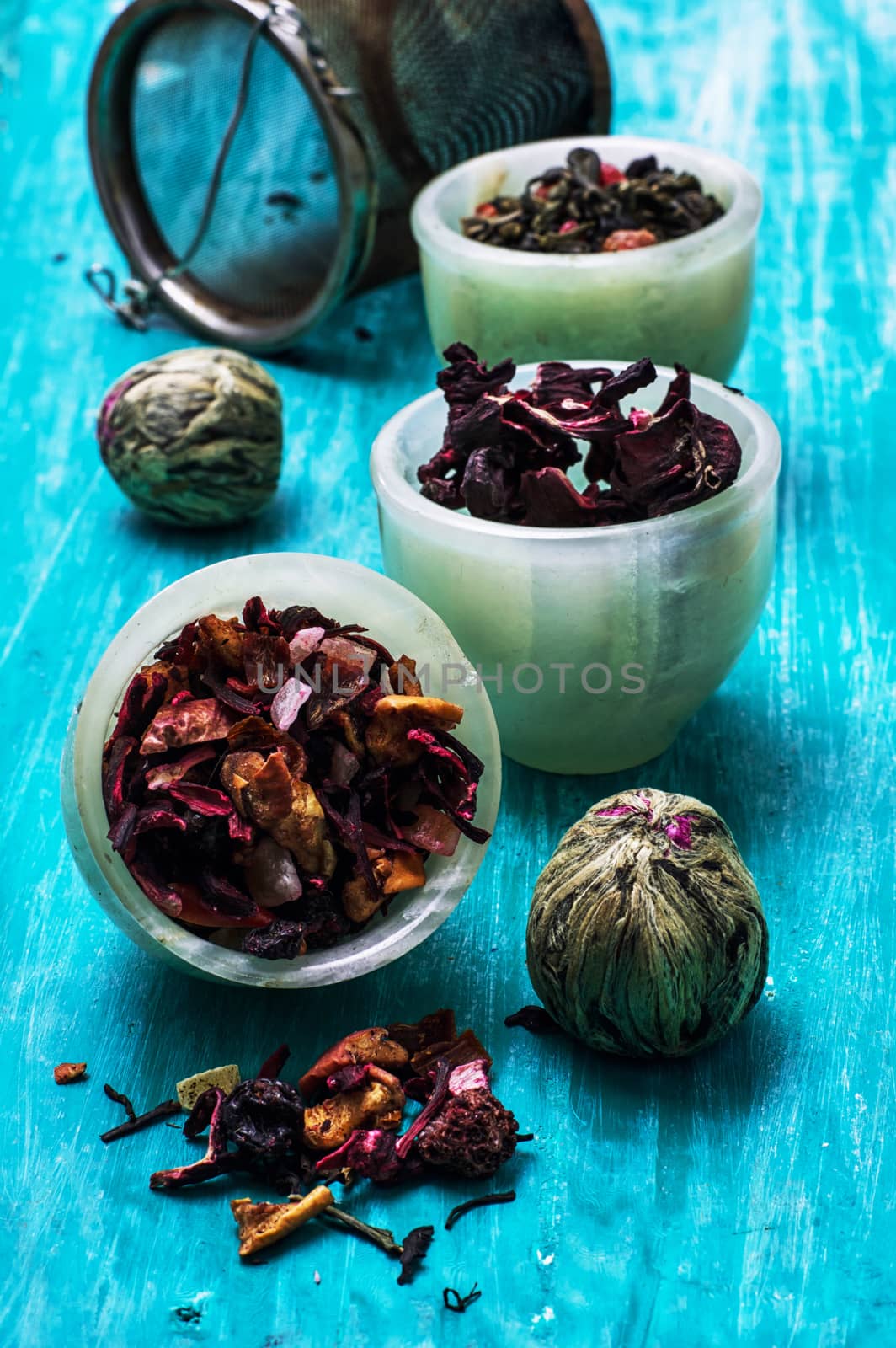 variety of dry tea leaves in jade stacks on turquoise wooden background.Toned image