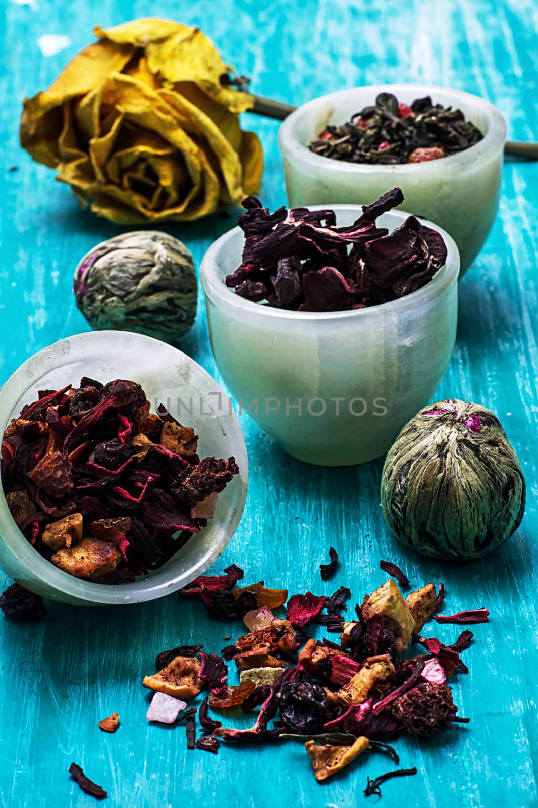 variety of dry tea leaves in jade stacks on wooden background by LMykola