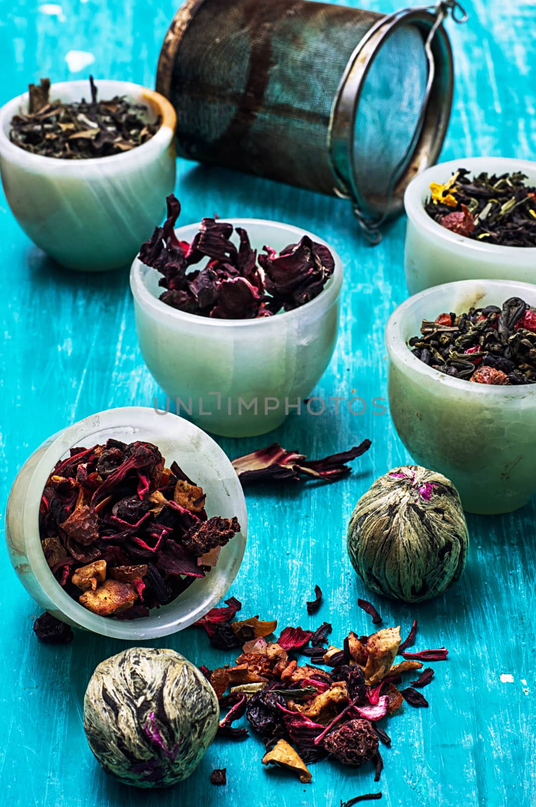 variety of dry tea leaves in jade stacks on turquoise wooden background.Toned image