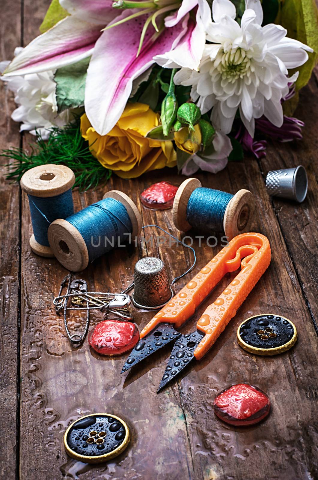 sewing accessories with a bouquet of fresh flowers.the image is tinted in vintage style