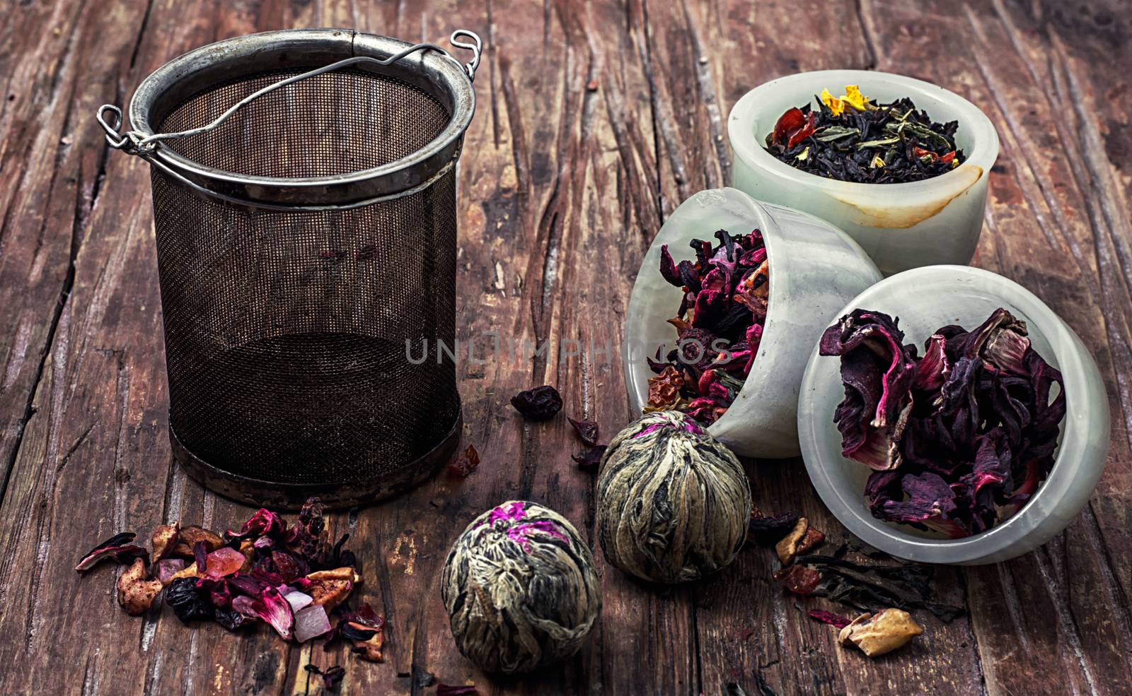 tea strainer and different varieties of tea leaves on wooden background.The toned image