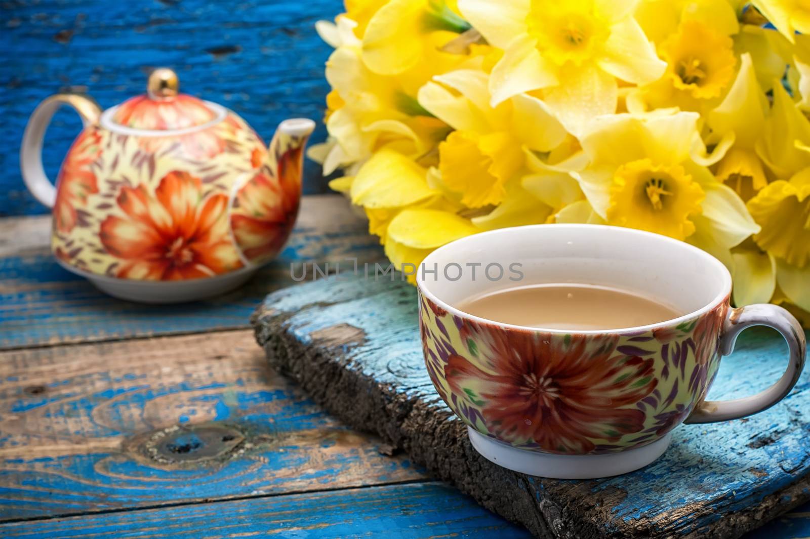 Cup of tea and a bunch of fresh daffodils.Selective focus