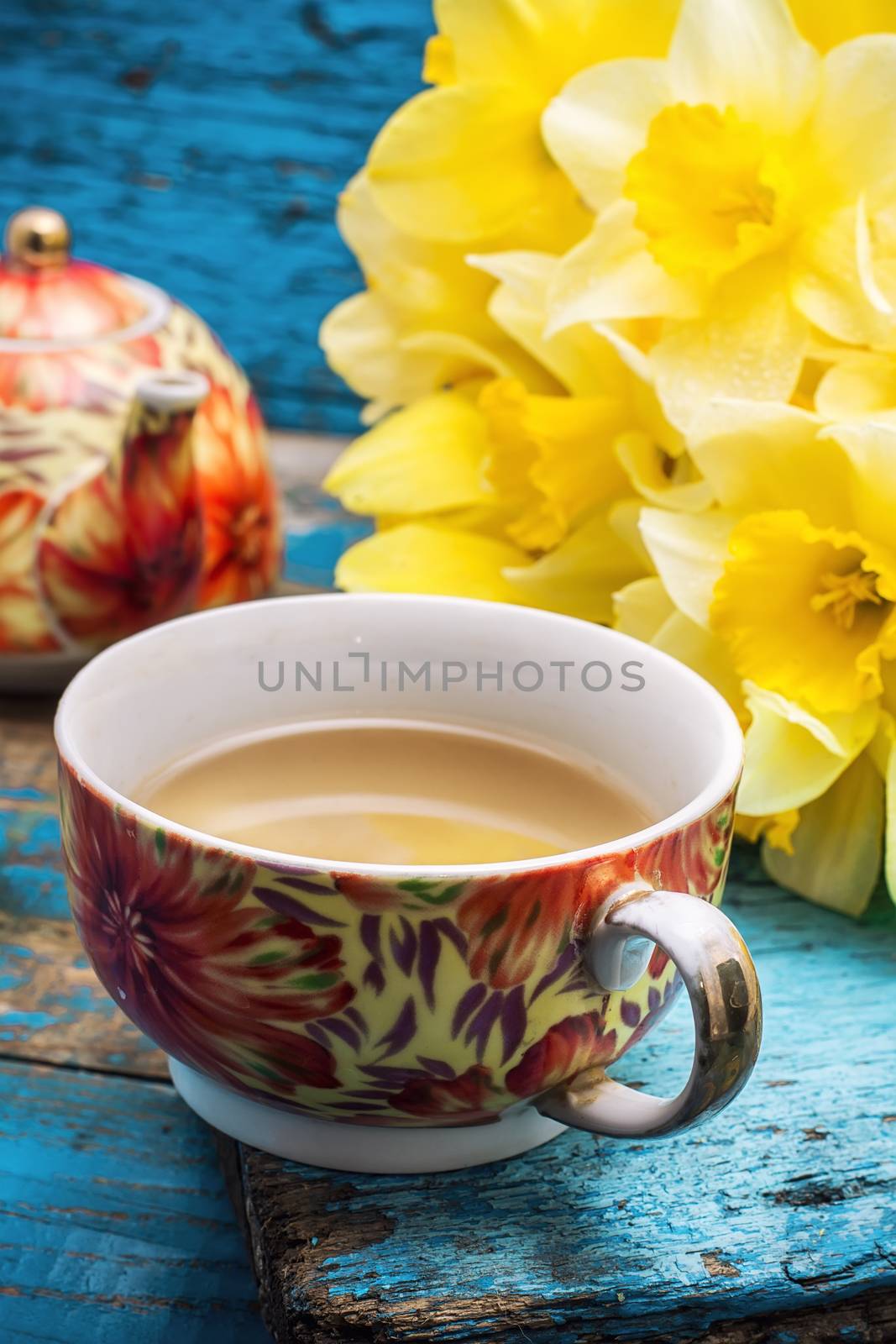 Cup of tea and a bunch of fresh daffodils.Selective focus