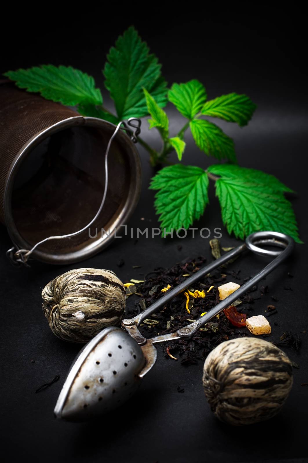 dry leaves of the tea infuser and accessories on black background