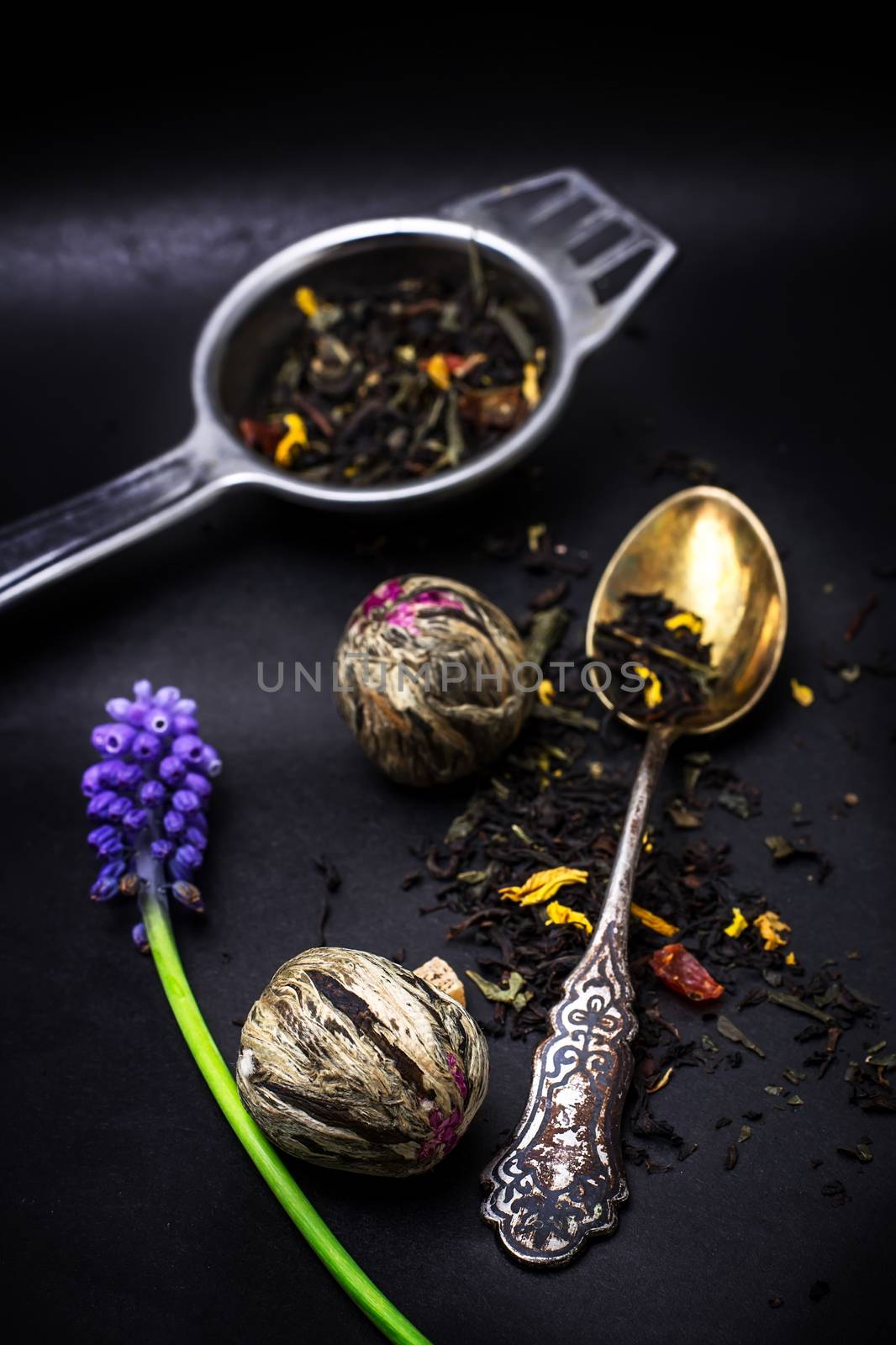 dry leaves of the tea infuser and accessories on black background