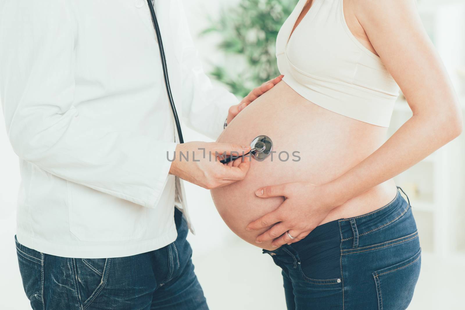 Pregnant woman examining by a doctor with a stethoscope