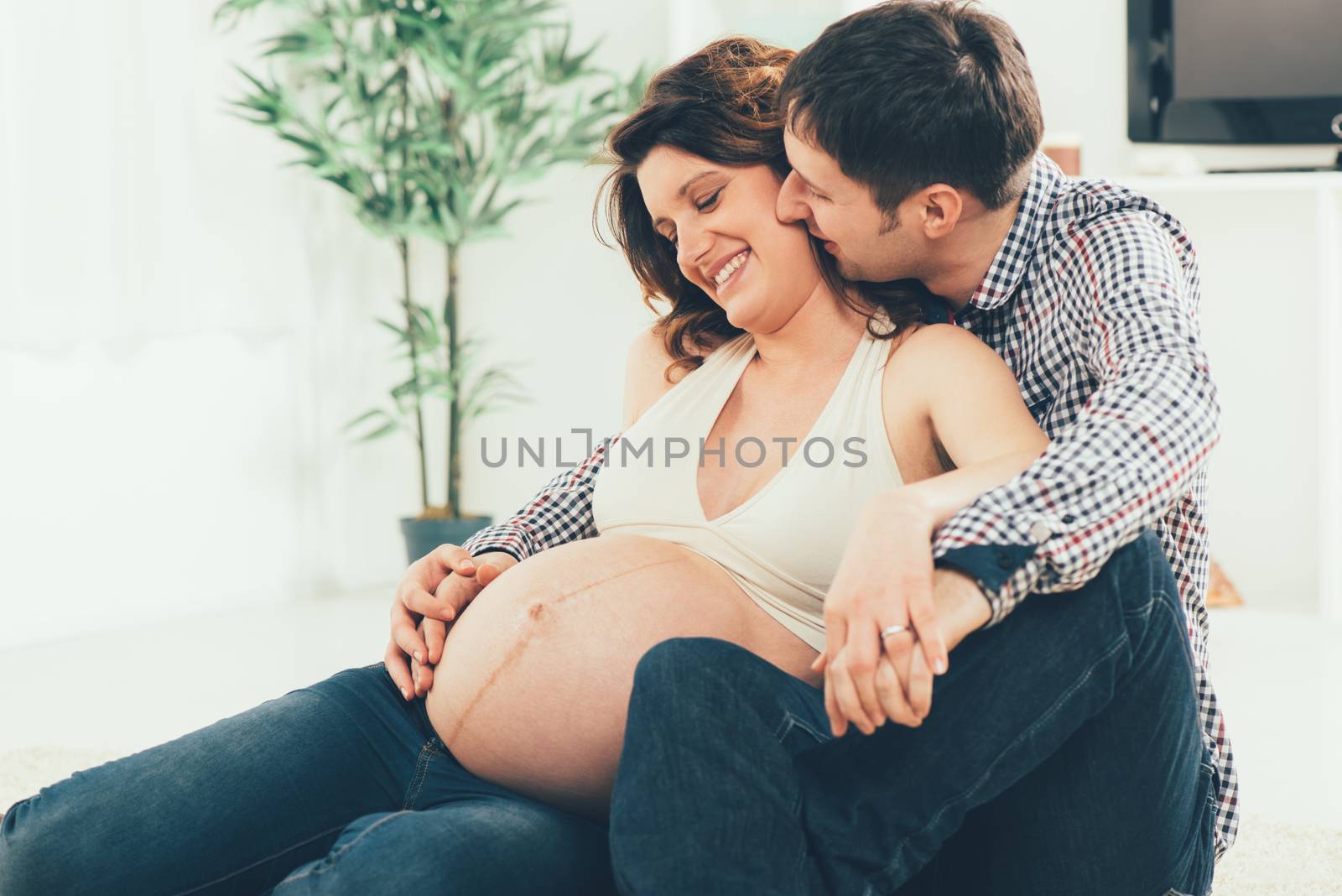 Portrait of a beautiful young couple cuddling the woman's pregnant belly. 