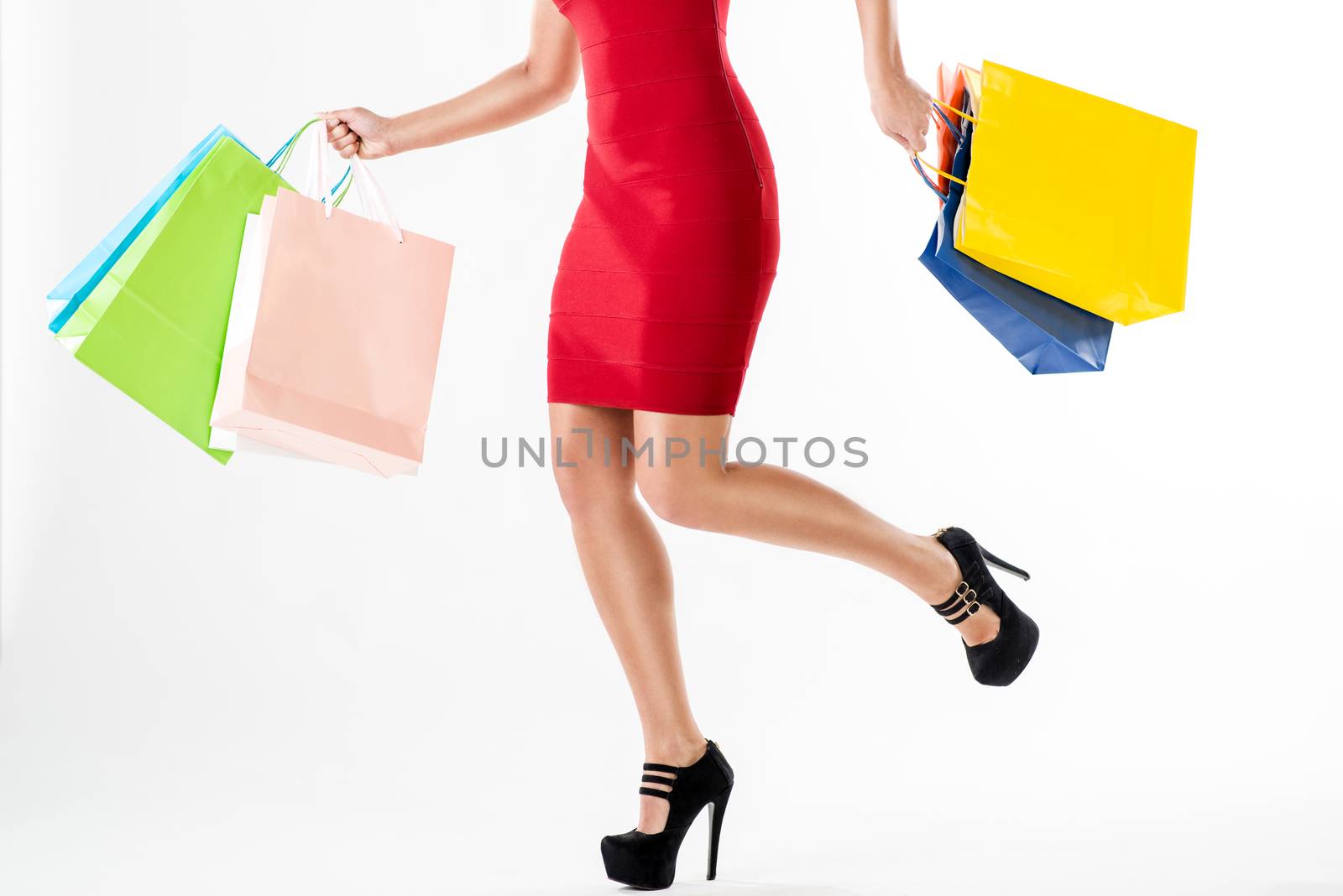 Close up of a woman legs and many shopping bags in hands after shopping. White background.