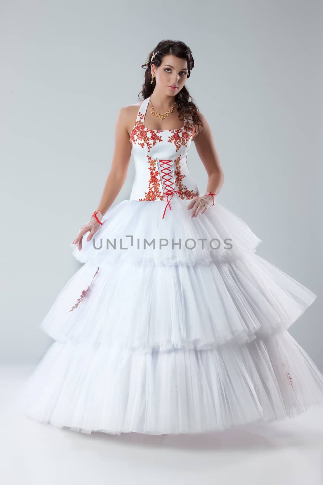 Young beautiful brunette in fashionable wedding dress on isolated studio background