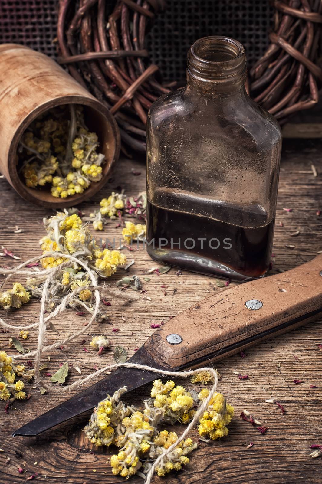 Herbs and glass bulb with decoction of them in rustic style.The image is tinted.