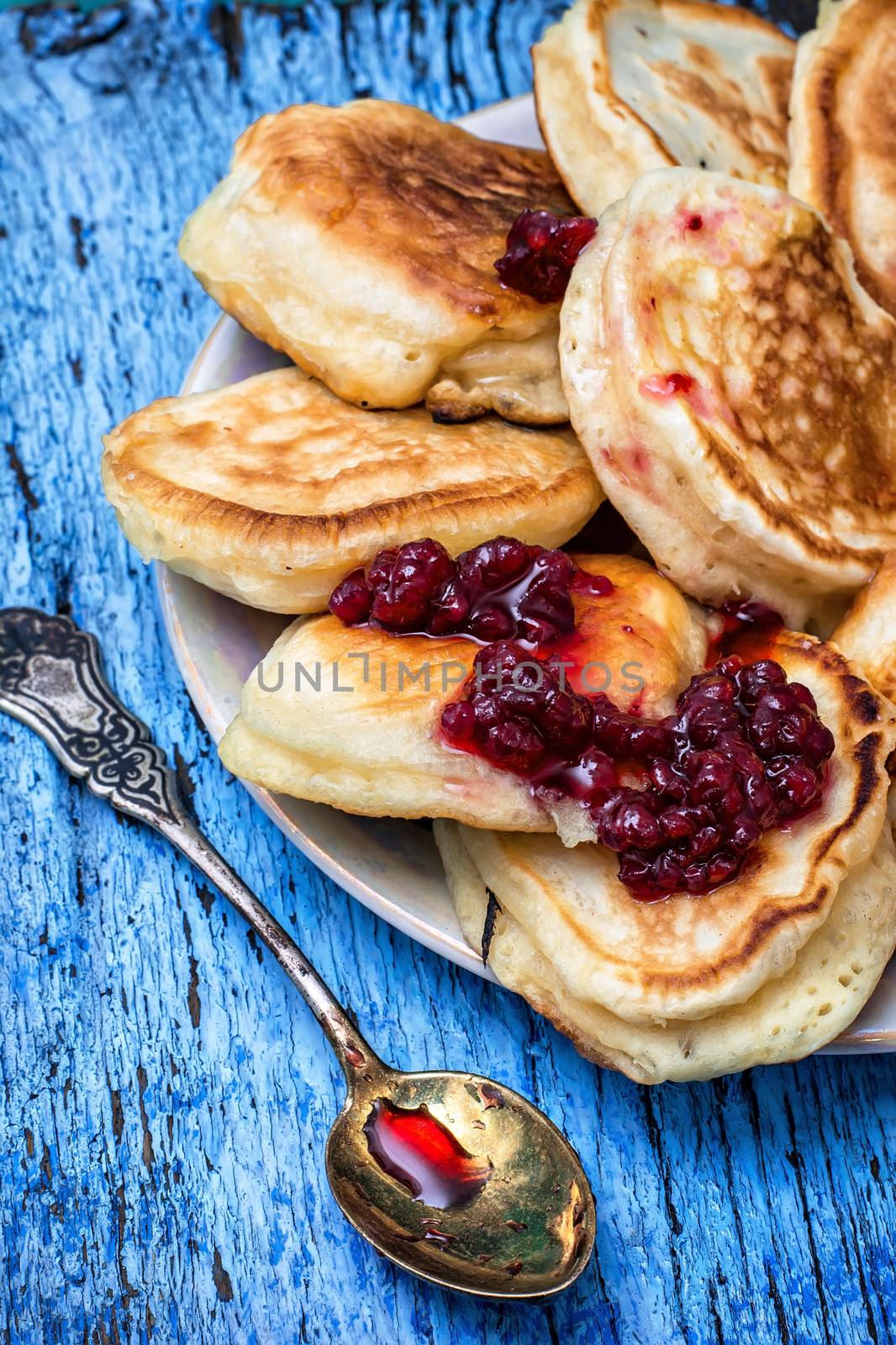 pancakes drizzled with jam on blue wooden board.