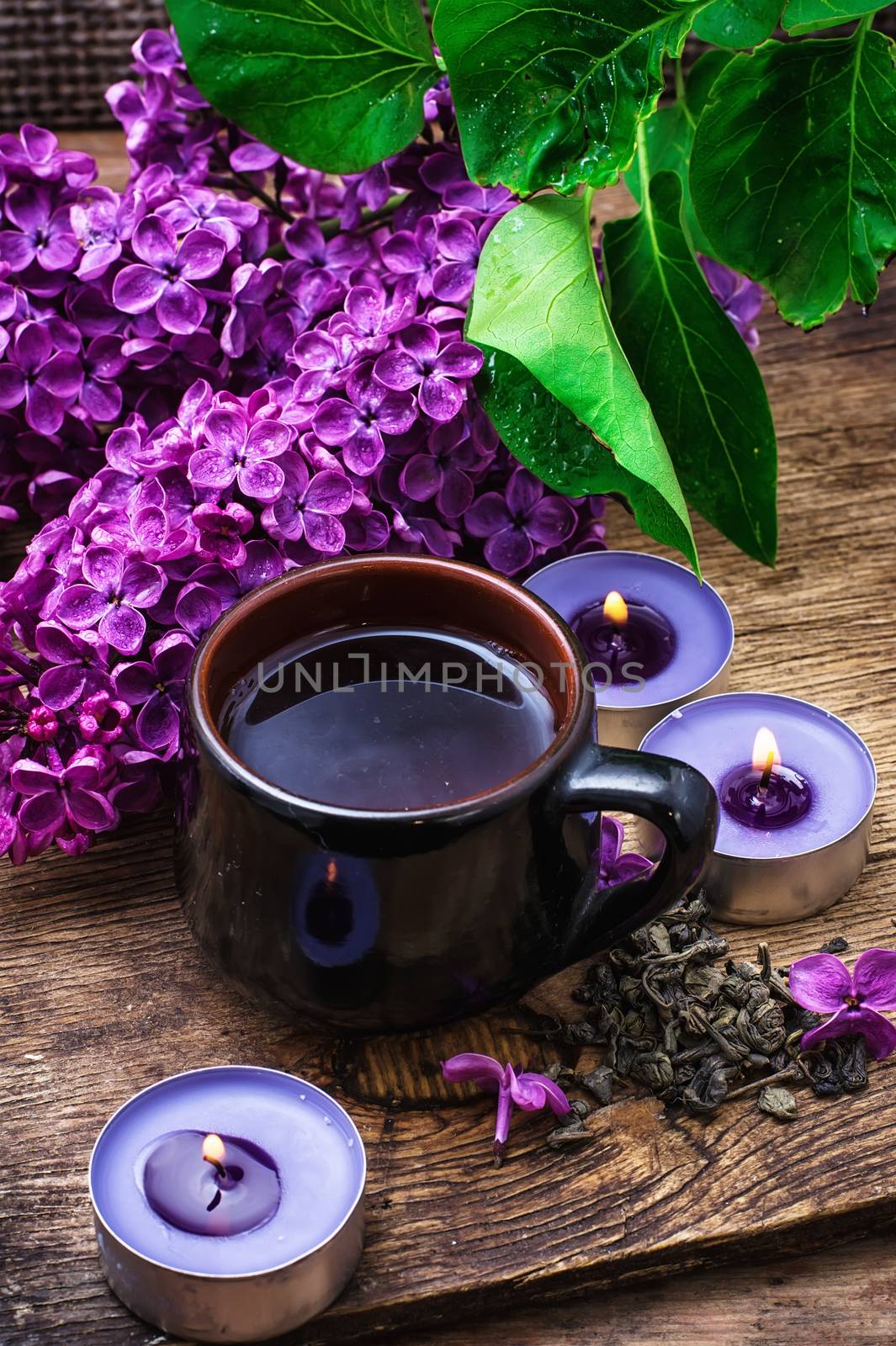 fragrant spring flower tea on the background of burning candles and lilac bouquet