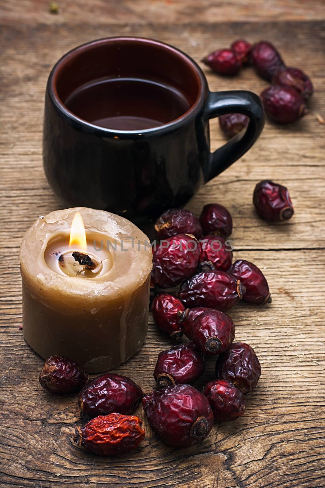 black cup tea on the background of scattered dried rose hips and wax candles.Selective focus