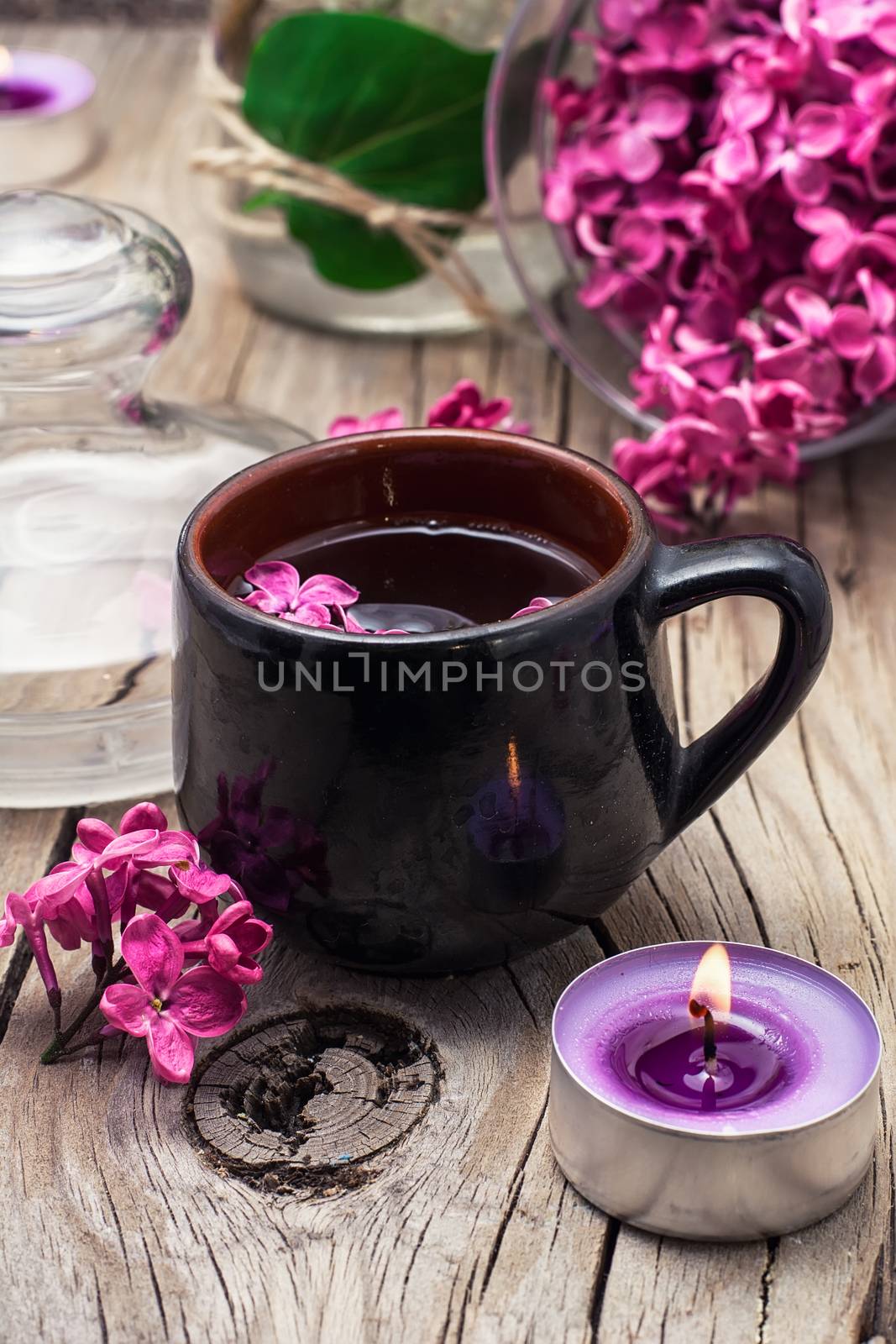 fragrant spring flower tea on the background of burning candles and lilac bouquet