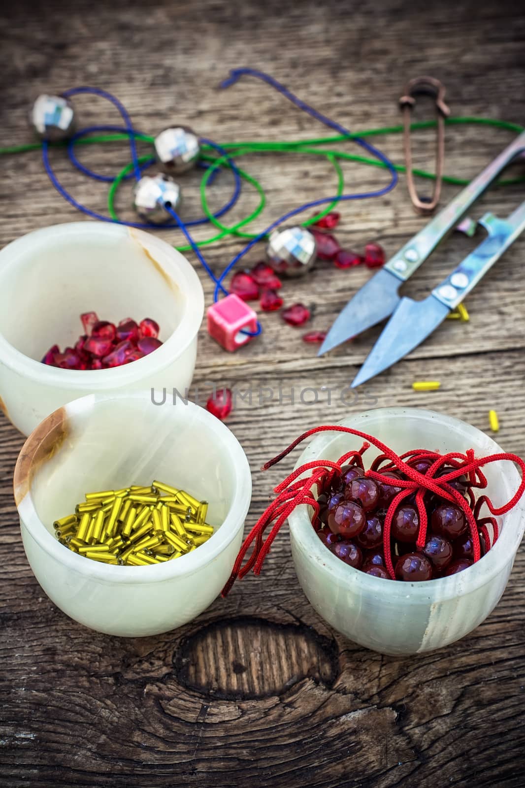 set of beads in stacks on wooden table with tools for needlework.Selective focus.Photo tinted