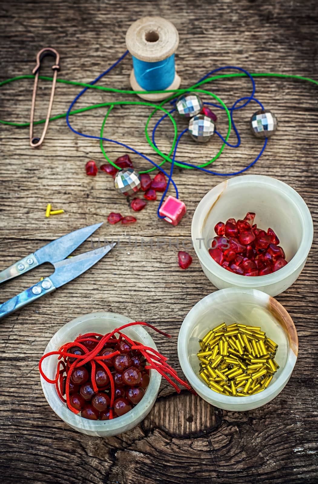 set of beads in stacks on wooden table with tools for needlework.Selective focus.Photo tinted