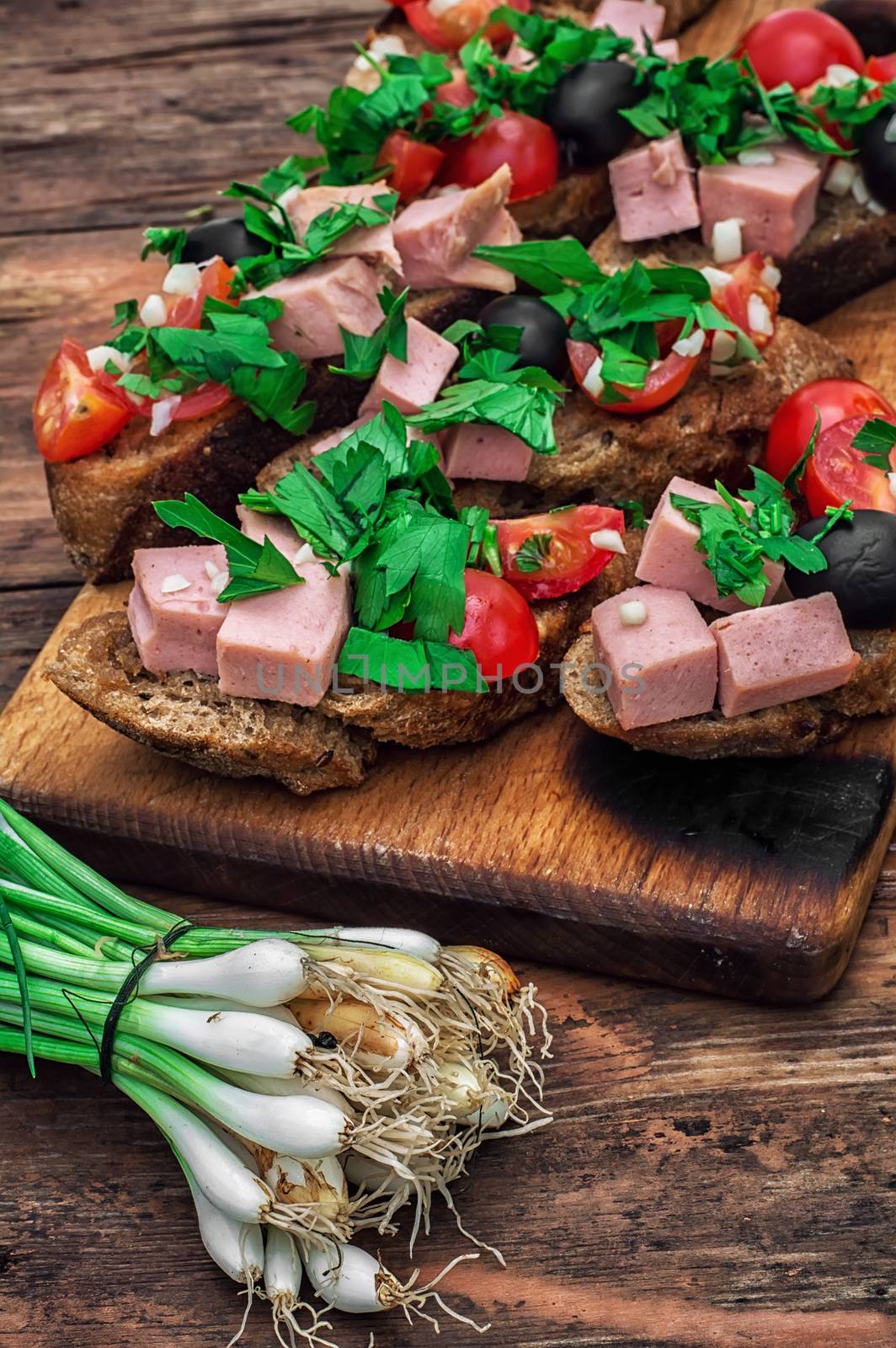 sandwiches with meat ,fresh tomatoes, onions and olives on wooden table top.Photo tinted
