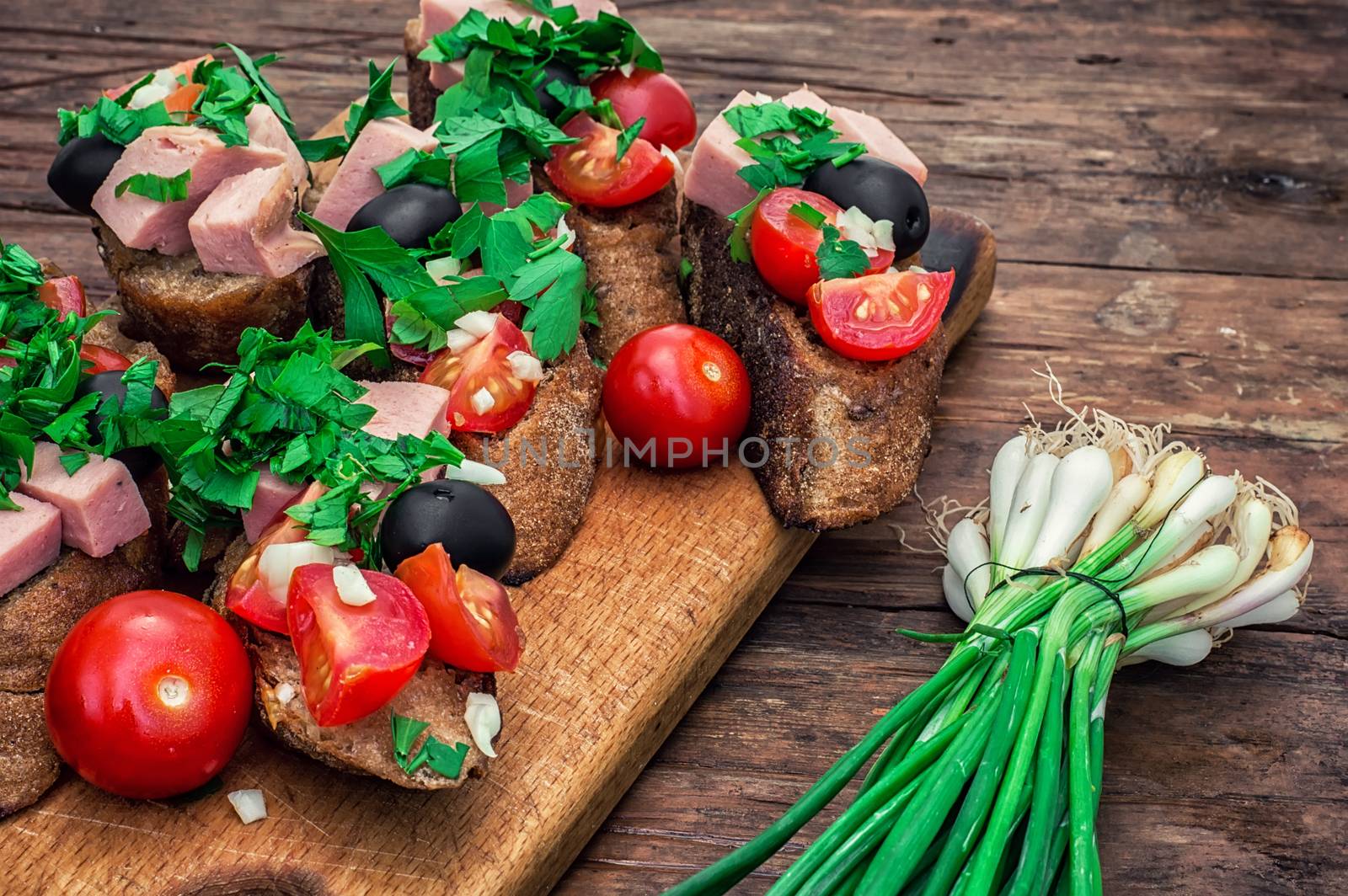 sandwiches with meat ,fresh tomatoes, onions and olives on wooden table top.Photo tinted