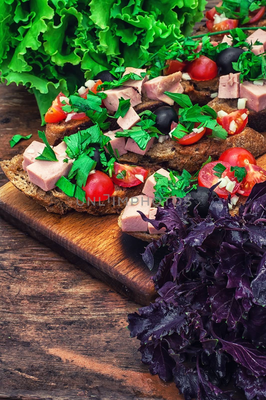 sandwiches with meat ,fresh tomatoes, onions and olives on wooden table top.Photo tinted