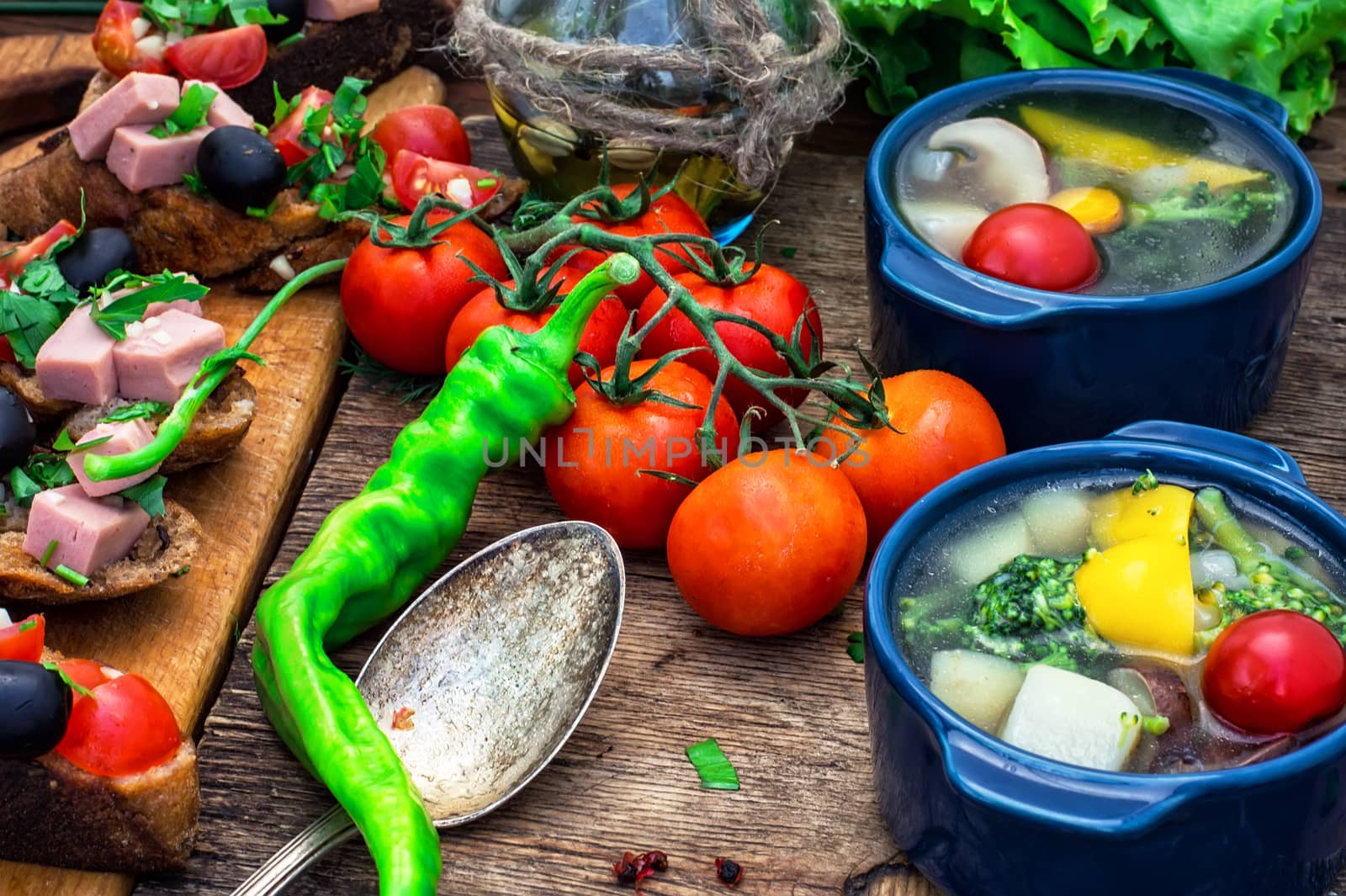 traditional soup of fresh vegetables in blue pot on wooden background.Photo tinted