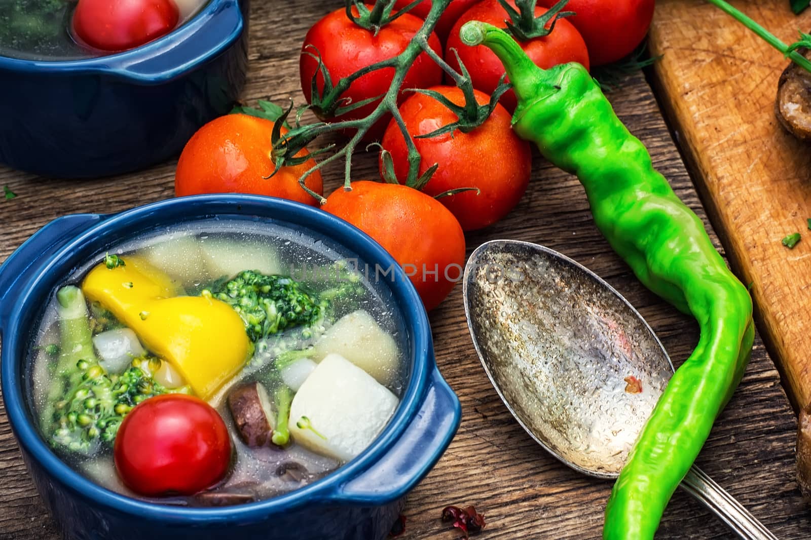 traditional soup of fresh vegetables in blue pot on wooden background.Photo tinted