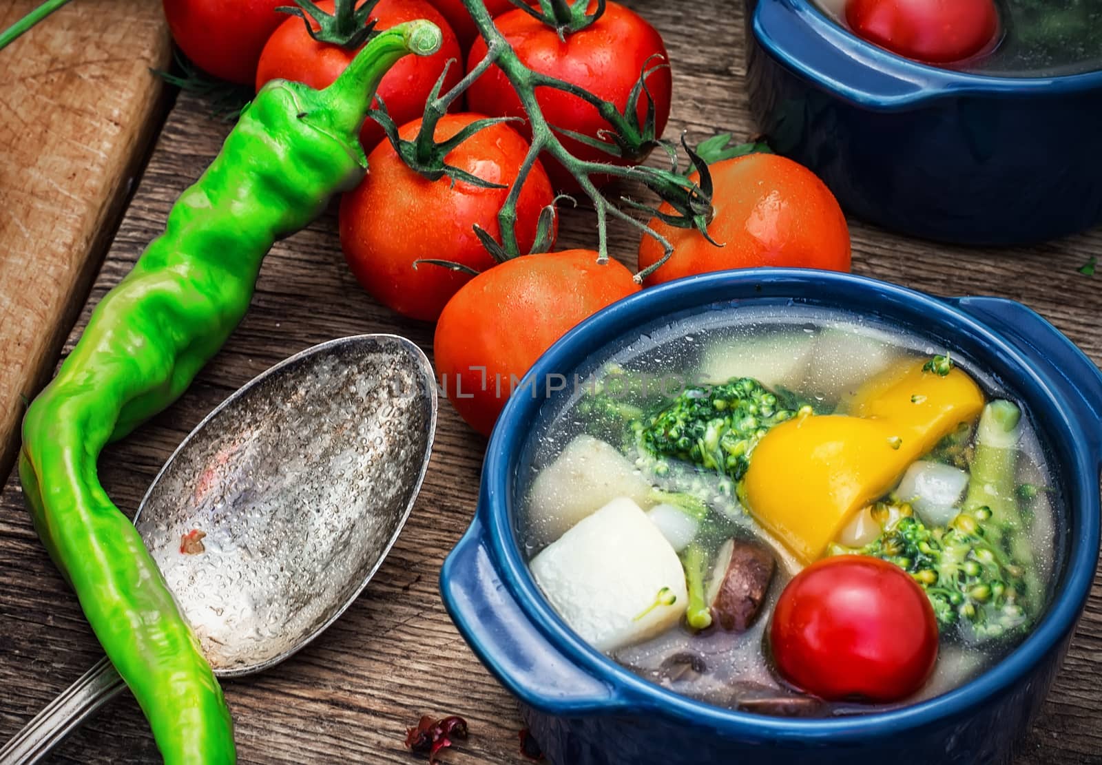 traditional soup of fresh vegetables in blue pot on wooden background.Photo tinted