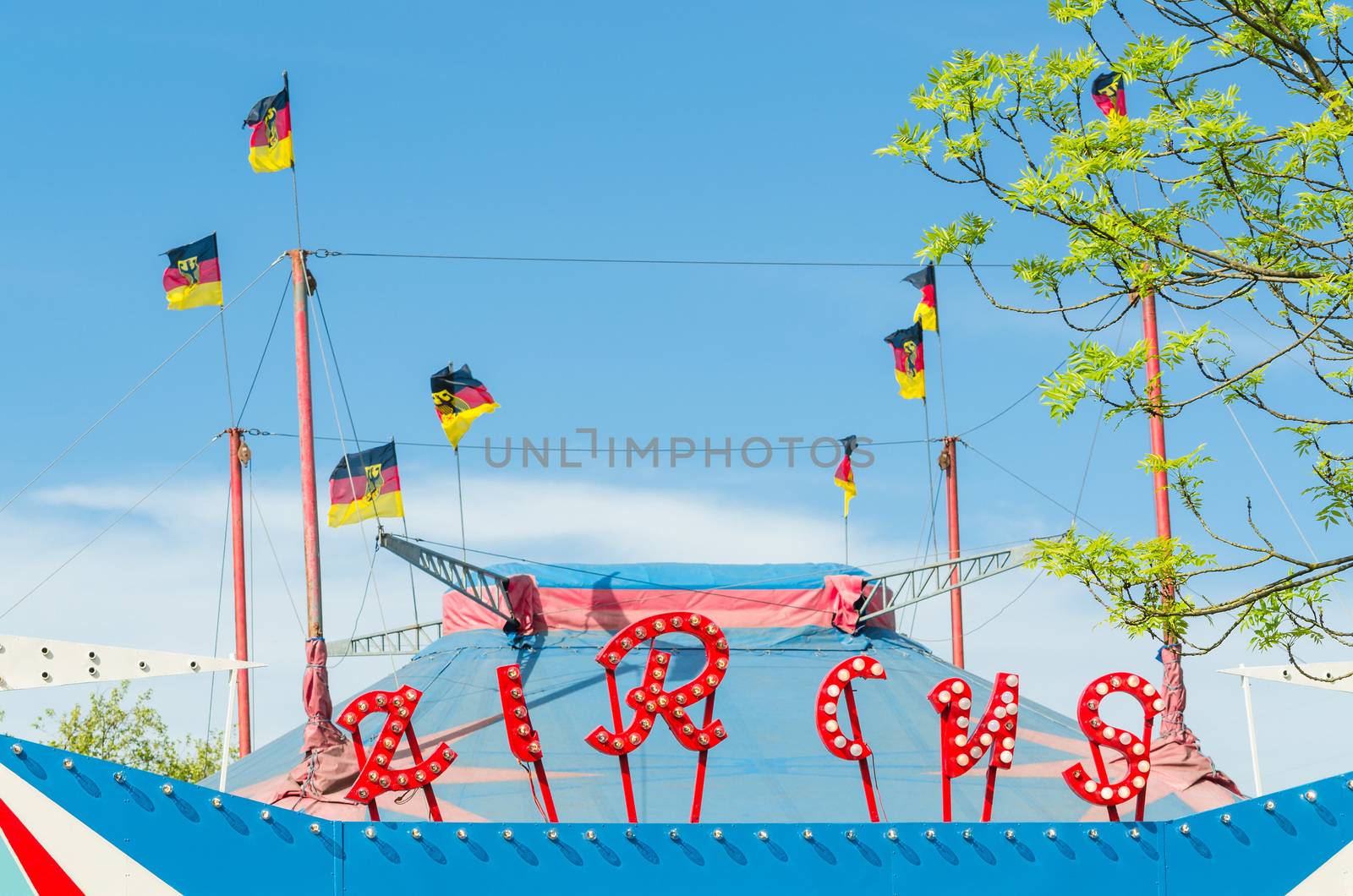 Beautiful colorful circus tent with flags in front of a bright blue sky.

