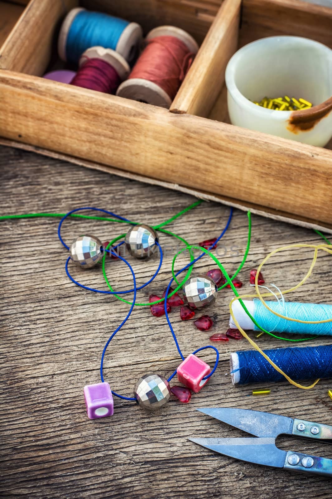 set of beads in stacks on wooden table with tools for needlework.Selective focus.Photo tinted