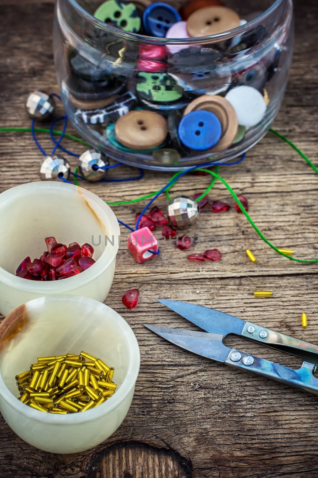 set of beads in stacks on wooden table with tools for needlework.Selective focus.Photo tinted