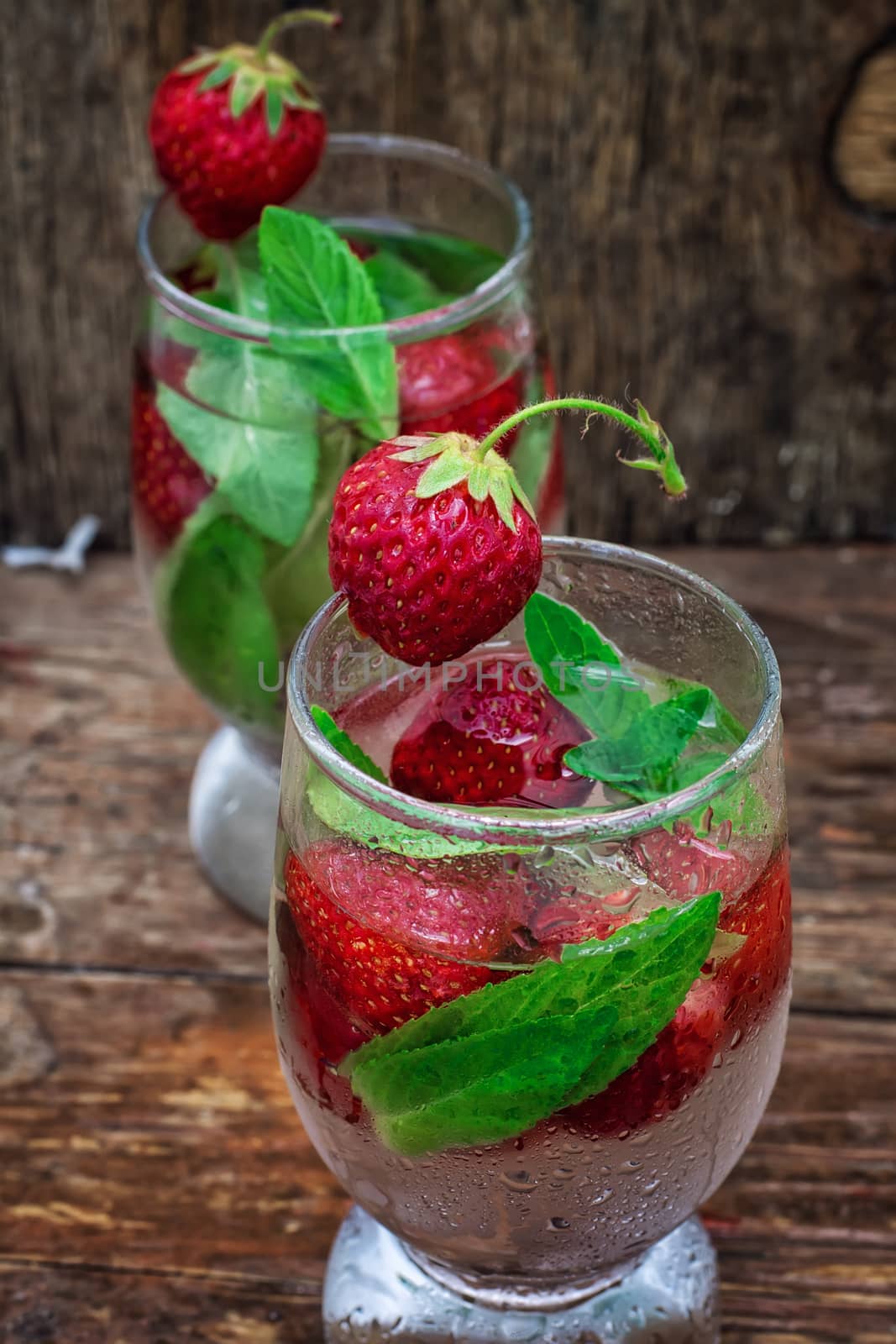 two glasses of alcoholic refreshing drink with mint and strawberries in vintage style.Selective focus.Photo tinted