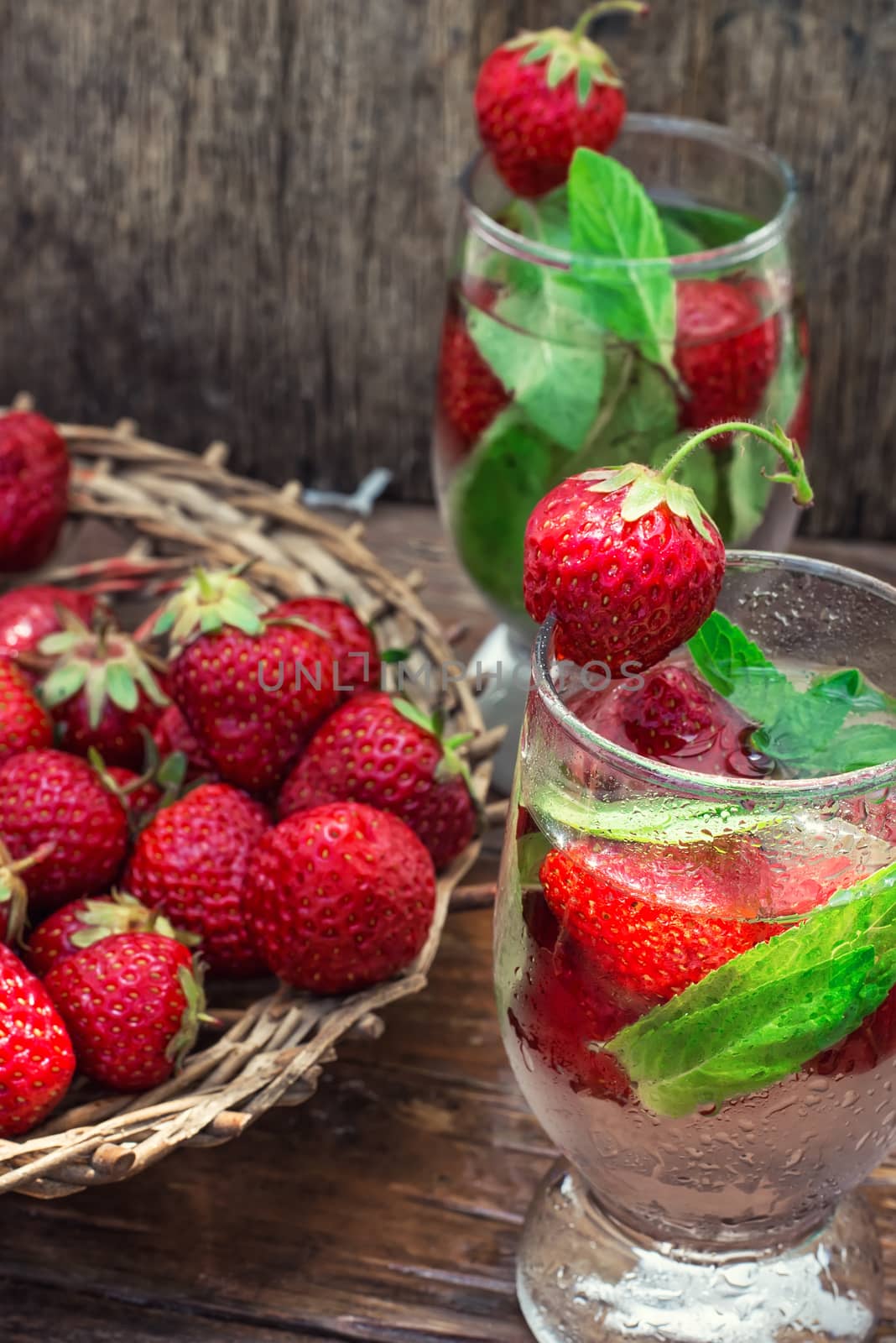 glass with drink of strawberries and mint on the background of the basket full berries.Selective focus.Photo tinted