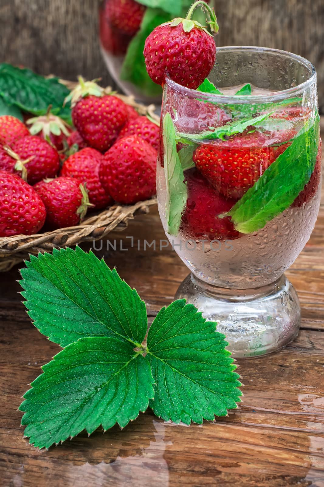glass with drink of strawberries and mint on the background of the basket full berries.Selective focus.Photo tinted