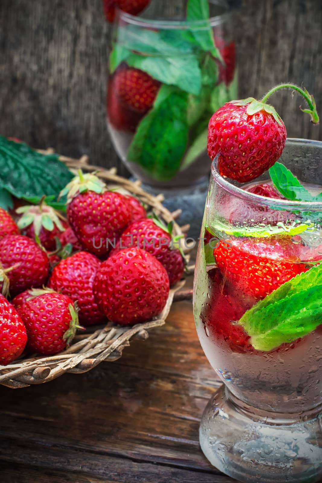 glass with drink of strawberries and mint on the background of the basket full berries.Selective focus.Photo tinted