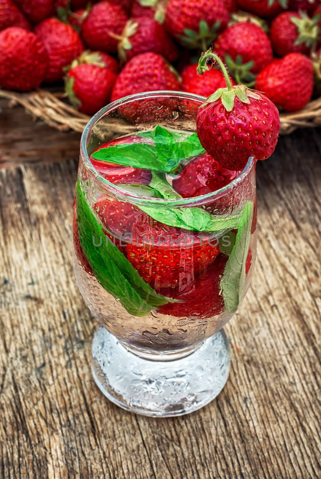 glass with drink of strawberries and mint on the background of the basket full berries.Selective focus.Photo tinted