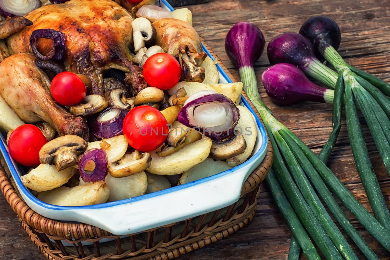 young chicken baked with potatoes,mushrooms and vegetables in the baking dish.