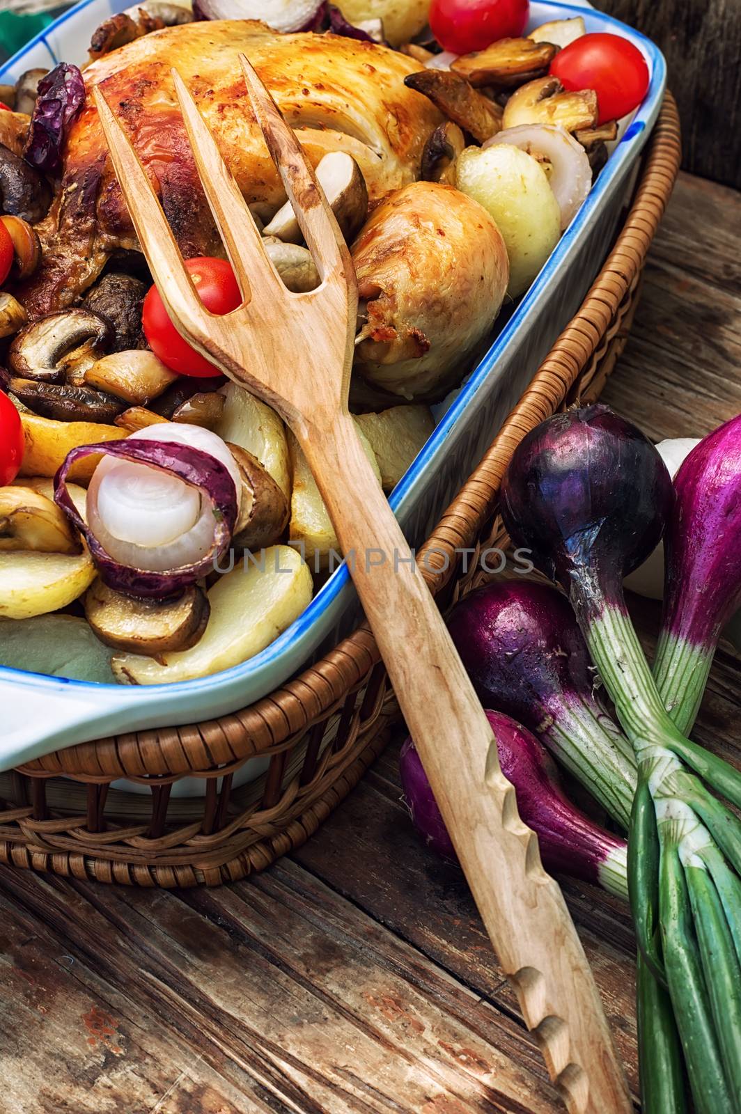 young chicken baked with potatoes,mushrooms and vegetables in the baking dish.