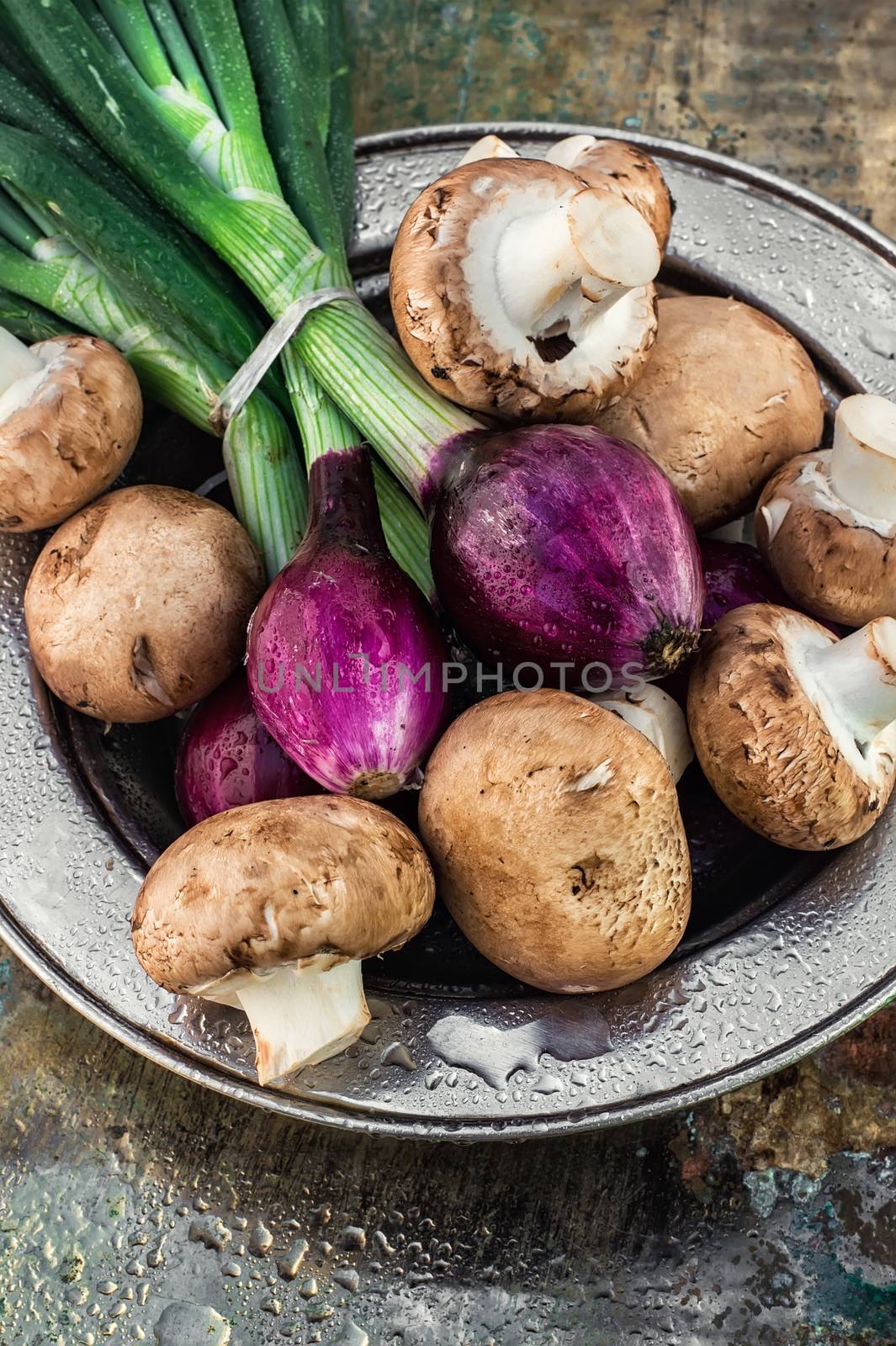 color onions and mushrooms on an iron plate in spray of water.Photo tinted.Selective focus