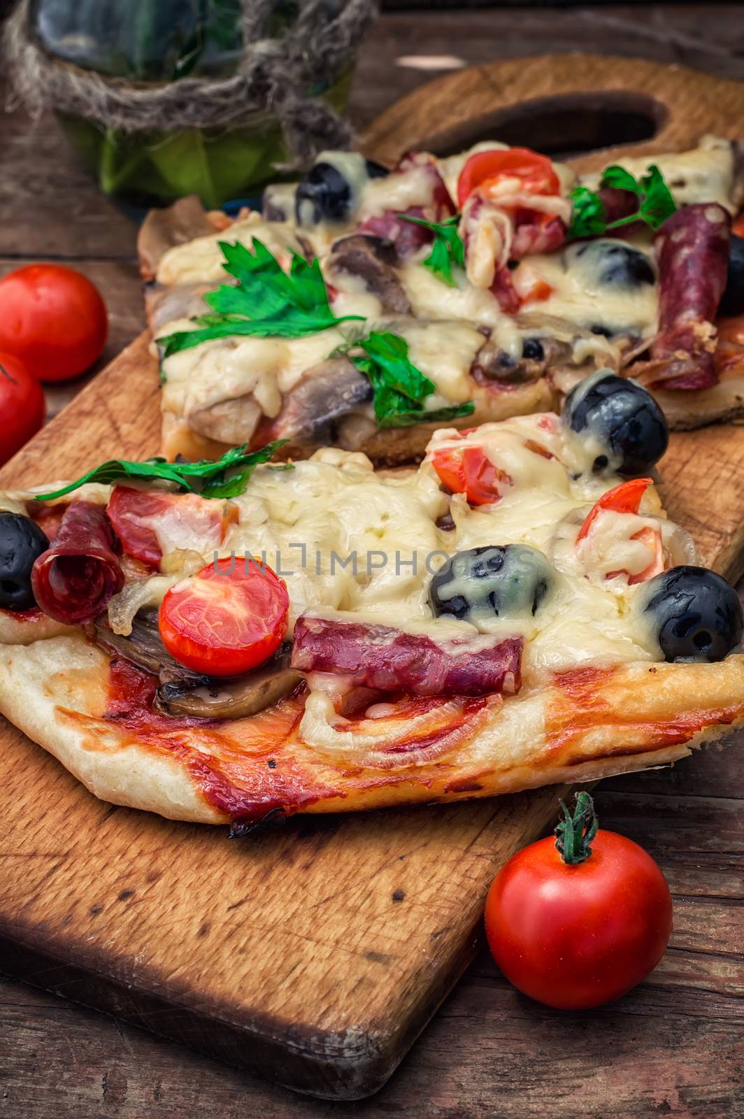 meat pizza made with salami,cheese,mushrooms,cherry tomatoes and olives.The image is tinted.Selective focus
