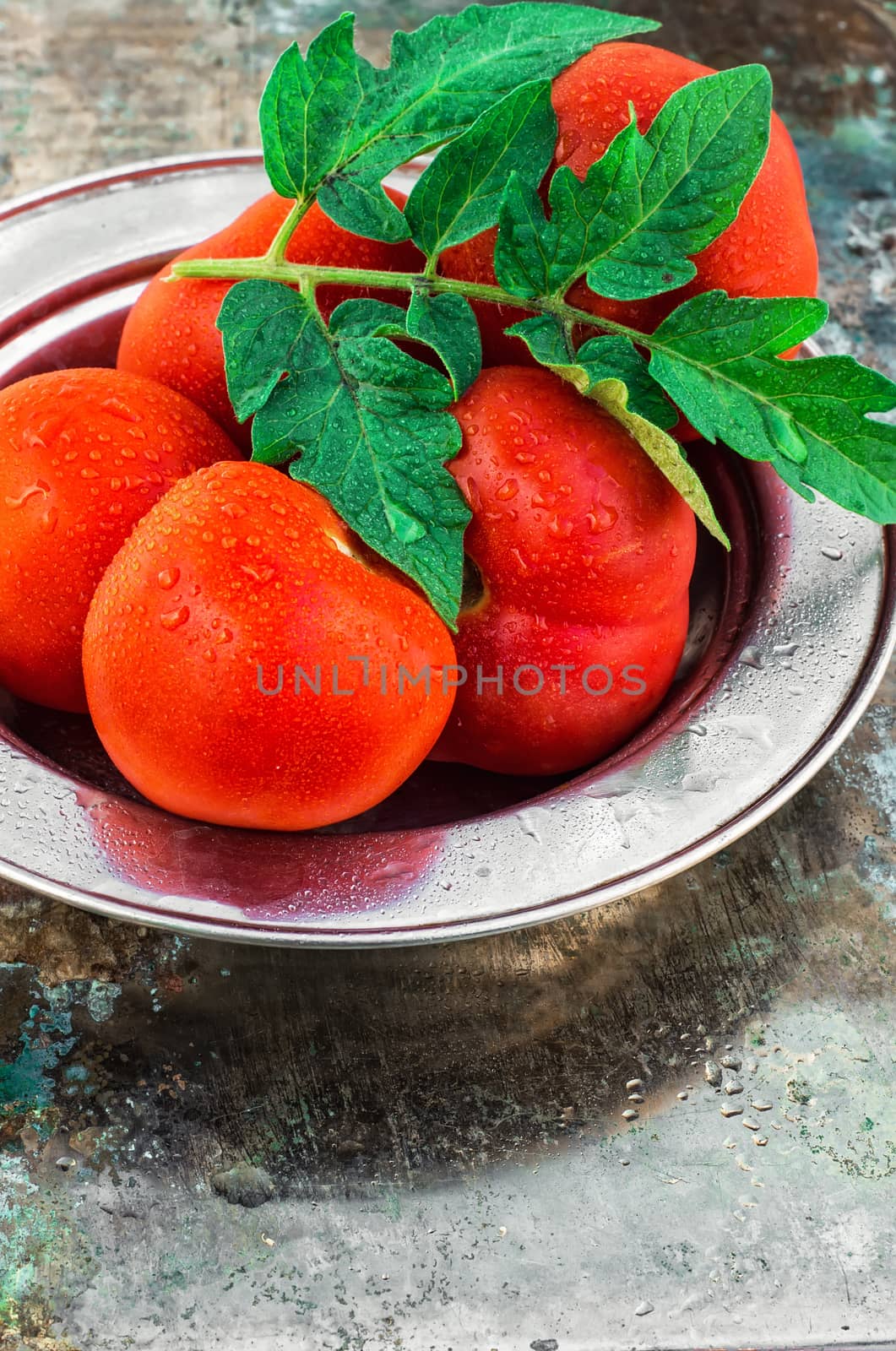 harvest of ripe tomatoes with green foliage on an iron plate